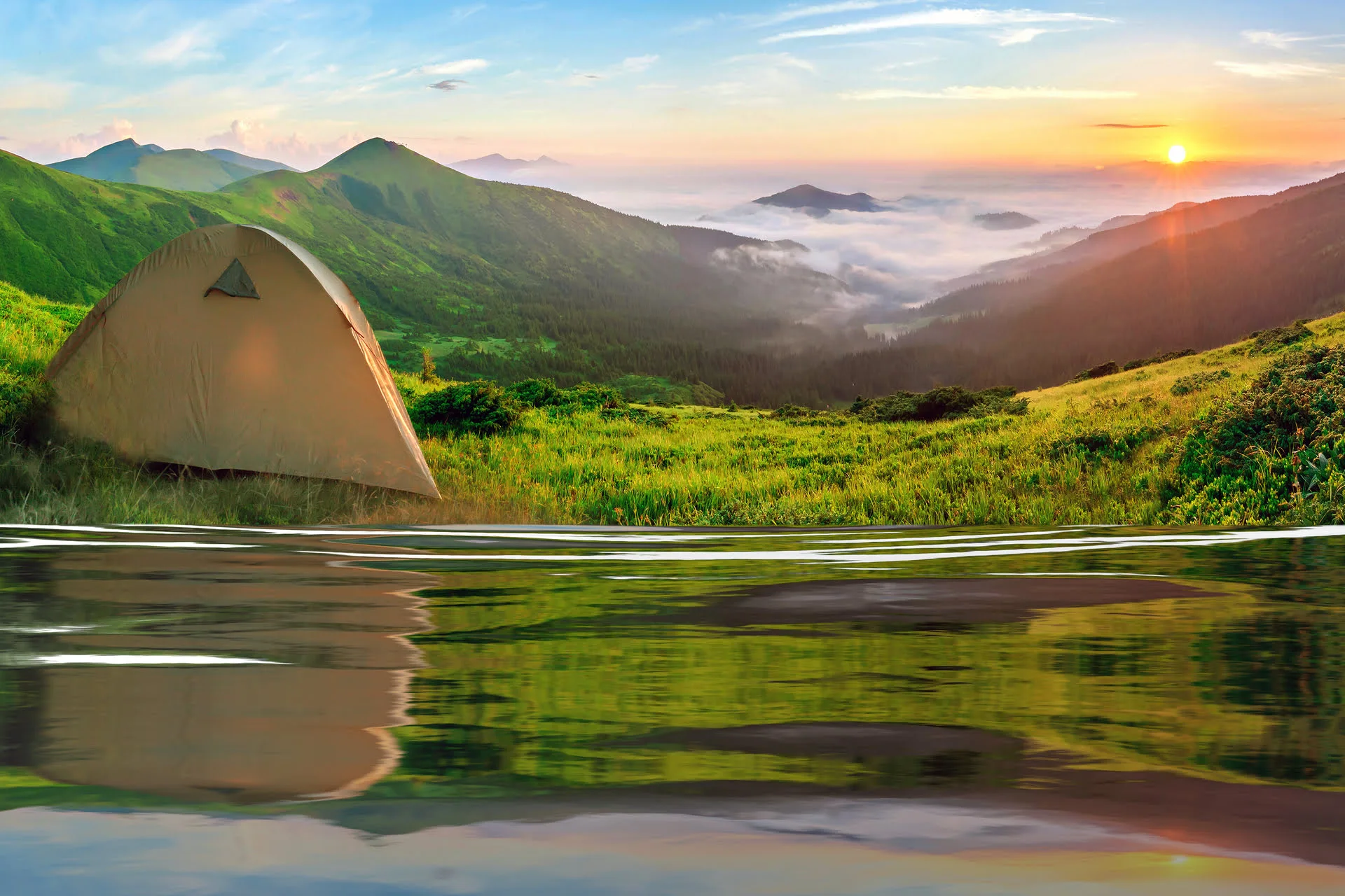 Camping setup near a lake with tent, chairs, and mountain scenery