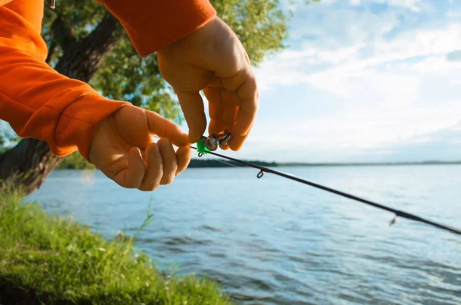 Hands preparing fishing tackle near the water
