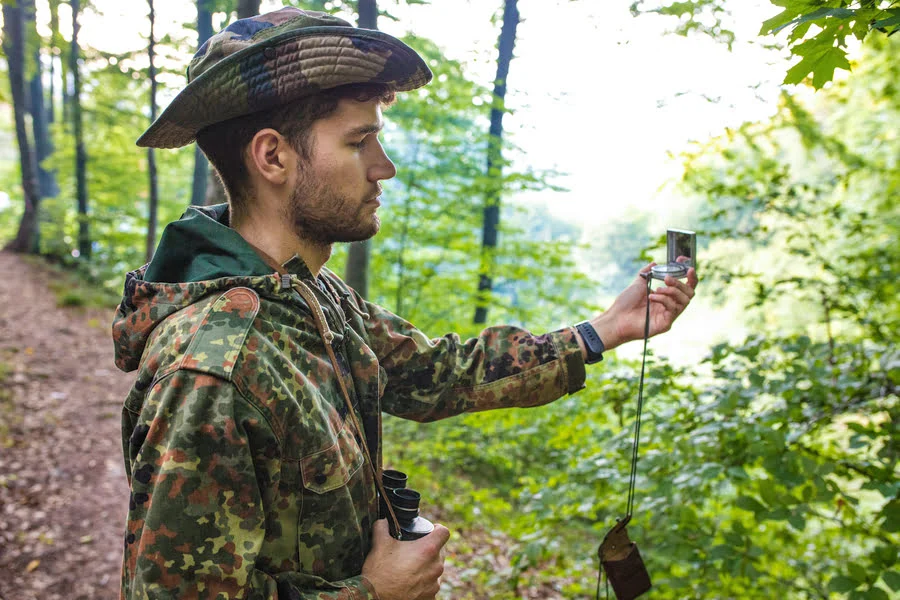 Hunter planning a route with map and equipment outdoors